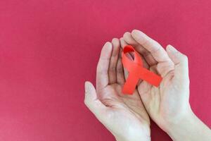 World Aids Day, AID red ribbon in hands on a red background photo