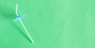 Top view of cocktail flexible straw with umbrella, on green background, straws for summer cocktails. photo