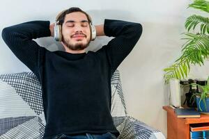 Frontal view of a young man with closed eyes listening to music. photo