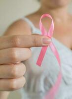 October Breast Cancer Awareness month, Woman in white dress with hand holding Pink Ribbon photo