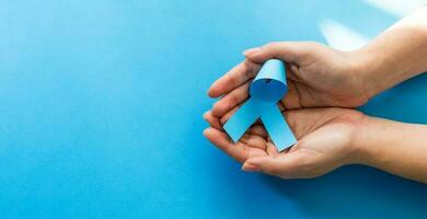 Woman hands with blue ribbons, Prostate Cancer Awareness. Male Health Care Concept. photo