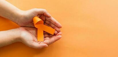 mujer manos con naranja cintas, leucemia cáncer conciencia y múltiple esclerosis conciencia. mundo cáncer día concepto. foto