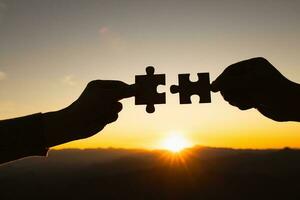 Concept of business, Silhouette of The man and woman holds in hand a jigsaw puzzle at sunset. Business solutions, success and strategy concept. photo