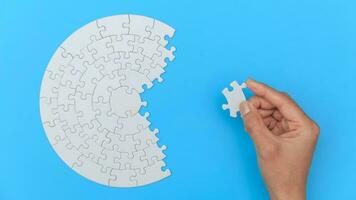 White jigsaw puzzle on a blue background. Completing final task, missing jigsaw puzzle pieces and business concept with a puzzle piece missing. photo