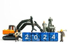 Miniature people , Worker team flips a block with the number 2024 photo