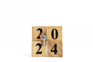 Miniature People Couple sitting On Wooden Block Number 2024 photo