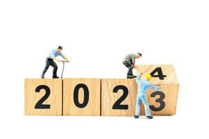 Miniature people , Worker team flips a wooden block with the number 2024 photo