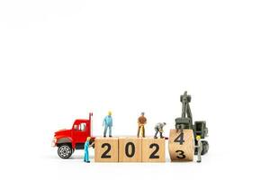 Miniature people , Worker team create a wooden block with the number 2024 photo