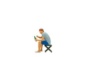 Miniature people Young man sitting on a lawn chair  isolated on white background photo