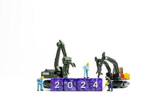 Miniature people , Worker team flips a block with the number 2024 photo