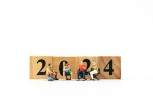 Miniature People sitting On Wooden Block Number 2024 photo