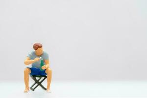 Miniature people Young man sitting on a lawn chair while clutching a water bottle. photo