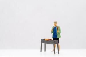 Miniature people Young man grilling BBQ photo