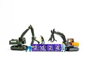 Miniature people , Worker team flips a block with the number 2024 photo