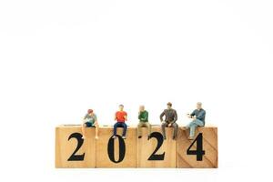 Miniature People sitting On Wooden Block Number 2024 photo