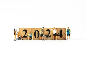 miniatura personas , un alegre familia disfruta nuevo años celebraciones con de madera bloquear 2024 foto