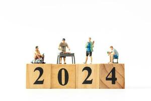 miniatura personas , un alegre familia disfruta nuevo años celebraciones con de madera bloquear 2024 foto