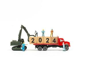 Miniature people , Worker team create a wooden block with the number 2024 photo