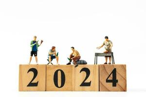 Miniature people , A joyful family enjoys New Year's celebrations with wooden block 2024 photo