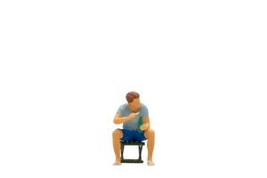 Miniature people Young man sitting on a lawn chair  isolated on white background photo