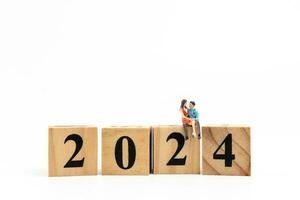 Miniature People Couple sitting On Wooden Block Number 2024 photo