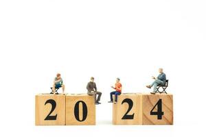 Miniature People sitting On Wooden Block Number 2024 photo