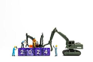 Miniature people , Worker team flips a block with the number 2024 photo