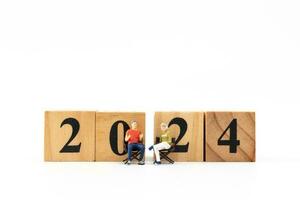 Miniature People Couple sitting On Wooden Block Number 2024 photo