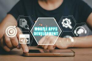 Mobile apps development concept, Person hand touching on smart phone on desk with mobile apps development icon on virtual screen. photo