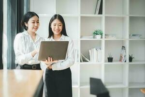 Two office workers talking with experienced colleague while using laptop computer in office, Colleagues discuss business, Business concept with copy space. photo