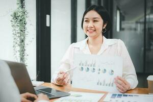 hembra operaciones gerente sostiene reunión presentación para un equipo de economistas asiático mujer usos negocio papel con crecimiento análisis, gráficos, Estadísticas y datos. foto