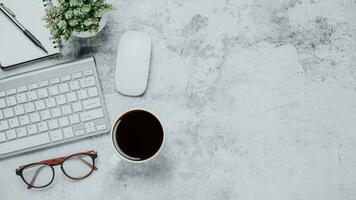 Top view, Modern white Office desk with keyboard computer, cup of coffee, pen, eyeglass and notebook, copy space, Mock up. photo