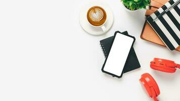 Top view, White Office desk with Headphone, Blank screen smart phone, pen, notebook and cup of coffee, copy space, Mock up. photo