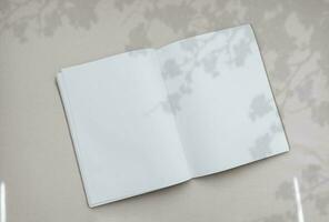 Flower Silhouette Shadow on Empty Book,Top view Open Note Book with Leaves shadow overlay on Canvas Texture Background,Flat lay Blank Diary mockup with white paper photo