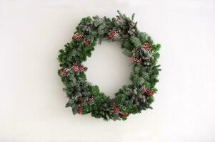 Christmas tree wreath with decorations hanging on a white wall photo