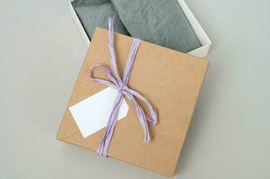 Boxes for parcels made of kraft paper on a gray background. Gift box with a tag for text, logo. photo