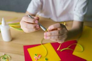 Making a postcard from long and narrow strips of paper twisted into spirals with an awl, quilling photo