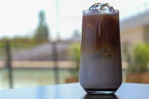 Iced coffee in glass cup or coffee latte on blurred background photo