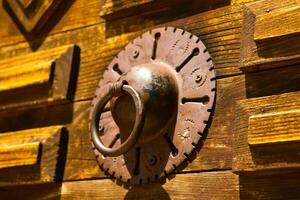 Close up shot of an old wrought iron knocker on a rustic wooden door photo