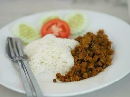 Southern Stir-Fried Pork with Yellow Curry Paste in white plate on table photo