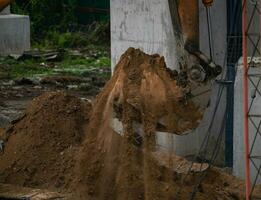 Backhoe working by digging soil at construction site. Bucket teeth of backhoe digging sand. Crawler excavator digging on soil. Excavating machine. Earthmoving machine. Excavation vehicle. Road repair. photo