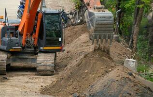 Digger working by digging soil at construction site. Bucket teeth of backhoe digging sand. Crawler excavator digging on soil. Excavating machine. Earthmoving machine. Excavation vehicle. Road repair. photo