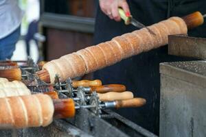 Baker cuting out a Trdelnik freshly made photo