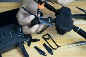 Professional mechanic repairing a drone with a small screwdriver on the table with various tools in modern workshop photo