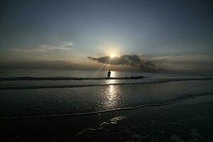 the beauty of the sunset on the beach with the silhouette of a fisherman photo