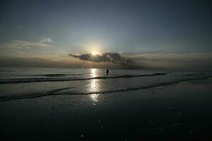 the beauty of the sunset on the beach with the silhouette of a fisherman photo