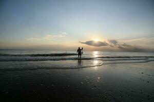 the beauty of the sunset on the beach with the silhouette of a fisherman photo