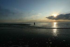 the beauty of the sunset on the beach with the silhouette of a fisherman photo