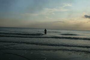 the beauty of the sunset on the beach with the silhouette of a fisherman photo