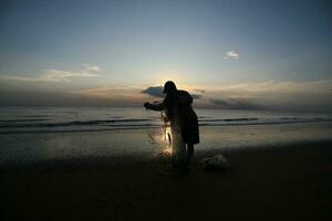 the beauty of the sunset on the beach with the silhouette of a fisherman photo